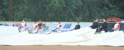 Members of the Mohawks work to get the tarp back on the field